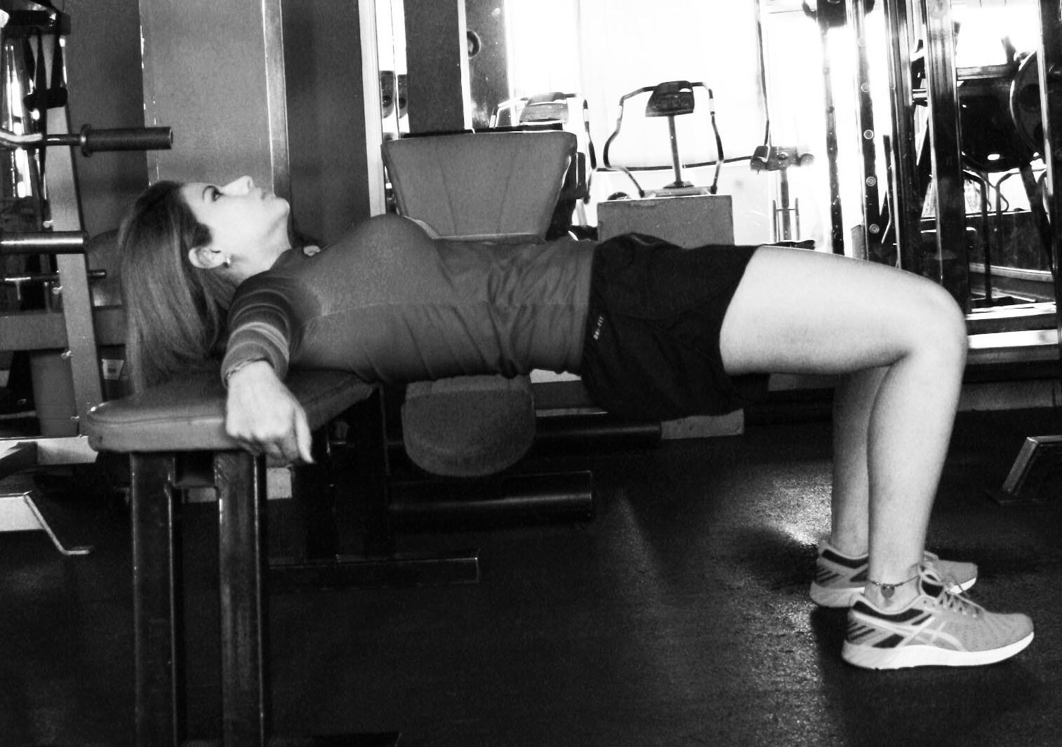 Mujer joven haciendo uno de los mejores ejercicios para aumentar glúteos: hip thrust